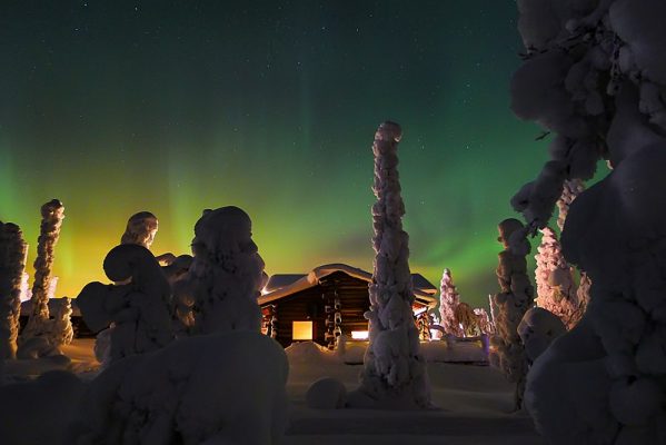 The aurora borealis lights up the sky around a cottage in Ruka, Finland